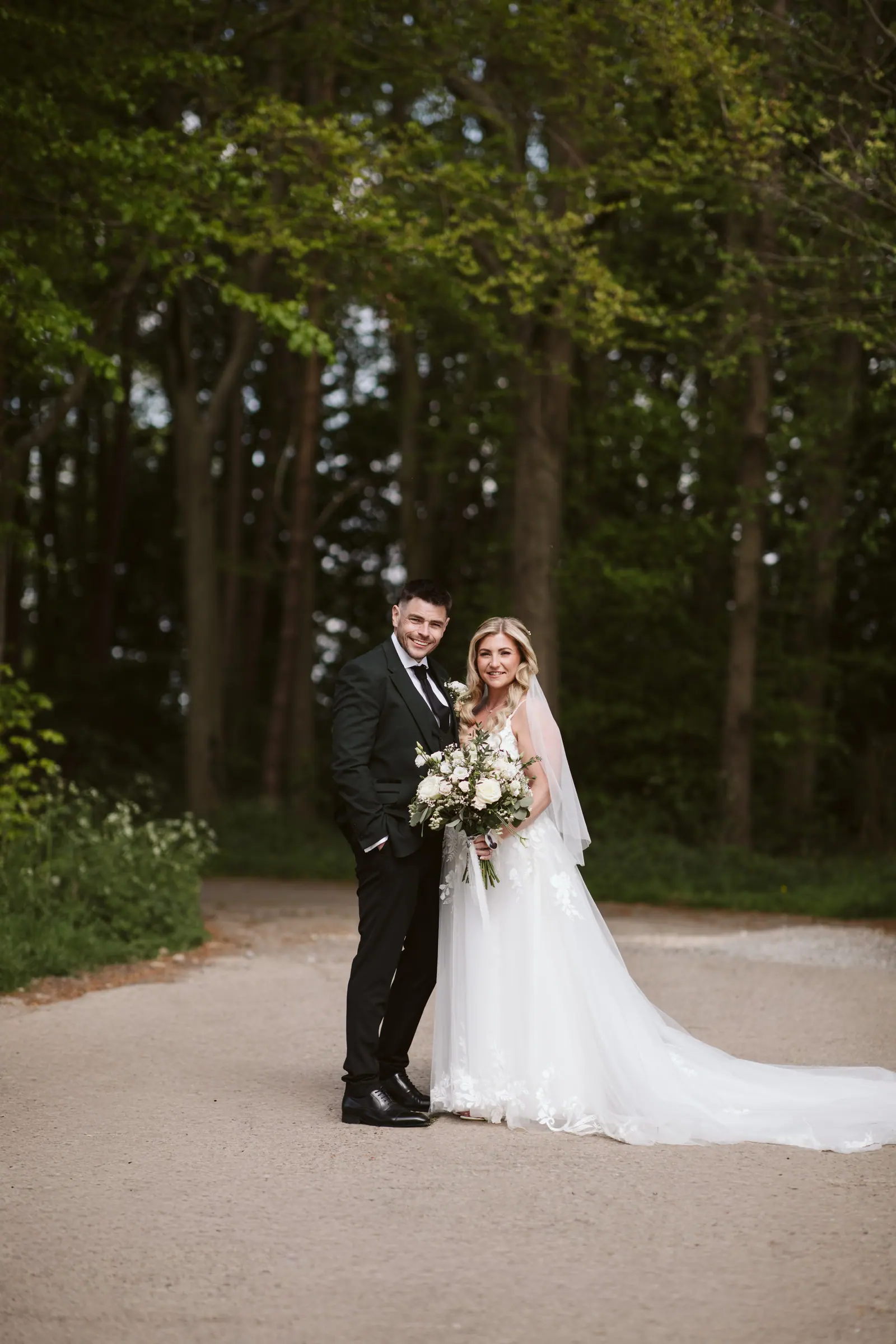 Lauren and Iain standing together at the entrance to the tree-lined lane